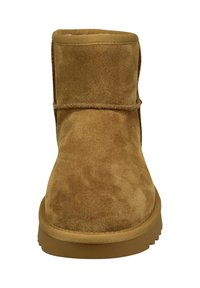 Tan-farbene Wildleder-Stiefelette in Mid-Calf-Höhe mit runder Zehenform und flacher Gummisohle, die an der Vorderseite eine schlichte, genähte Naht für Details aufweist.