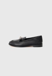 Black leather loafer with a textured finish, rounded toe, and a decorative metallic accent on the vamp. Low profile sole.