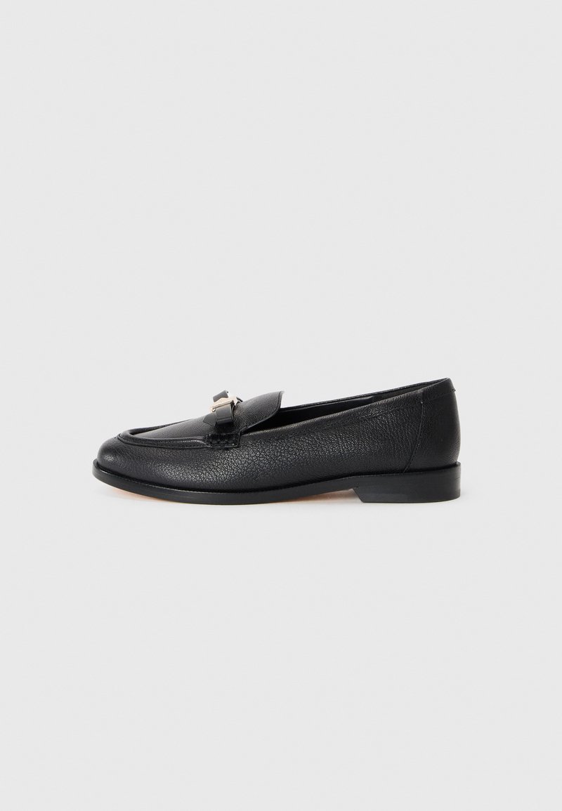 Black leather loafer with a textured finish, rounded toe, and a decorative metallic accent on the vamp. Low profile sole.