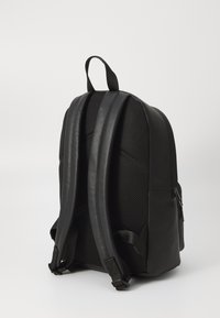 Zaino nero caratterizzato da un materiale testurizzato con pannelli in rete. Ha spallacci imbottiti e una maniglia superiore per un facile trasporto.