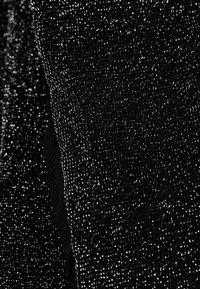 Tissu noir texturé avec un motif scintillant et moucheté. Il présente des variations subtiles de brillance et de densité, créant une apparence dynamique.