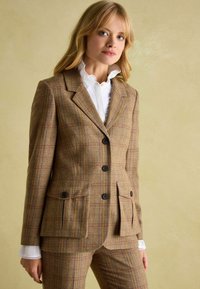 Hnedý károvaný sako vyrobené z textúrovaného materiálu, s klopovým golierom, tromi gombíkmi, bočnými vreckami a kontrastným prešívaním na manžetách.