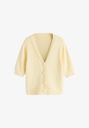 Ljusgul kofta med V-ringning, korta ärmar, ribbade muddar och fåll, med hjärtformade knappar längs framsidan. Mjuk textur.