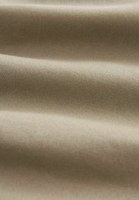 Beige szövet, finom bordázott textúrával, puha eséssel és finom fénycsillámmal. Sima felszín, egységes színárnyalattal.