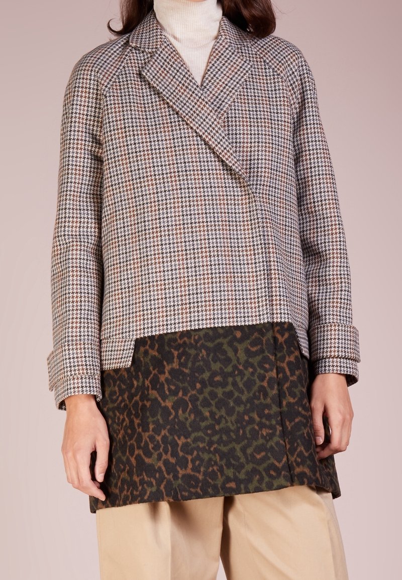 Dobbeltradet frakke med hundetandsmønster i beige og brun, med en kontrasterende mørkegrøn og brun leopardprint nederste sektion.