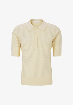 Svetlo rumena pletena polo majica s kratkimi rokavi, teksturiranim vzorcem, petimi gumbi ter rebrastim ovratnikom in spodnjim robom. Mehak tekstilni občutek.