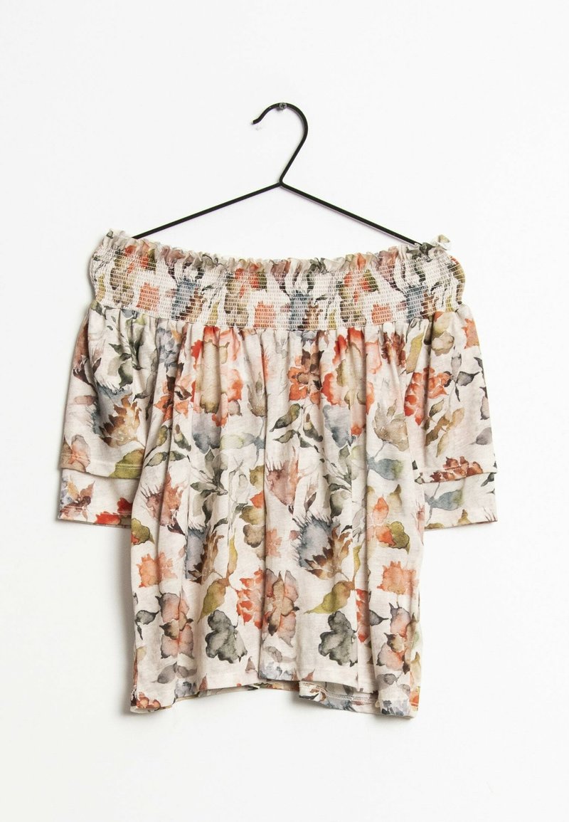 Blouse décolletée épaules avec manches 3/4, encolure smockée et motif floral dans des tons orange doux, vert, gris et beige, suspendue sur un cintre noir.