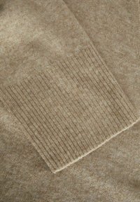 Ljusbrun tröja med en slät textur och ribbade ärmslut, med ett subtilt melerat mönster och en avslappnad passform.