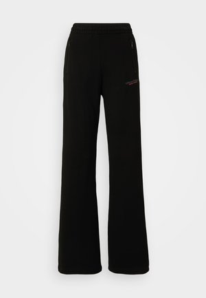 Pantaloni della tuta neri con vestibilità ampia, vita elastica, due tasche con zip e dettaglio del logo rosso sulla gamba. Tessuto morbido.