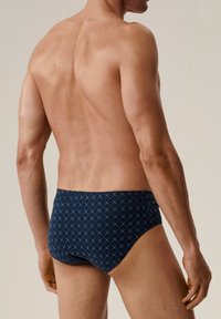 Granatowe kąpielówki wykonane z elastycznego materiału, zdobione wzorem w diamenty. Projekt zawiera niski krój oraz bezszwowe krawędzie dla większego komfortu.