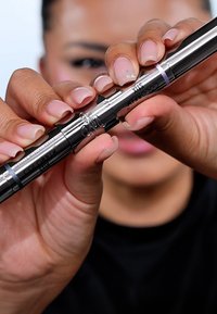 Stylo cosmétique en métal argenté à double embout avec des accents bleus. Dispose d'un mécanisme à vis et d'une marque claire. Forme cylindrique lisse.