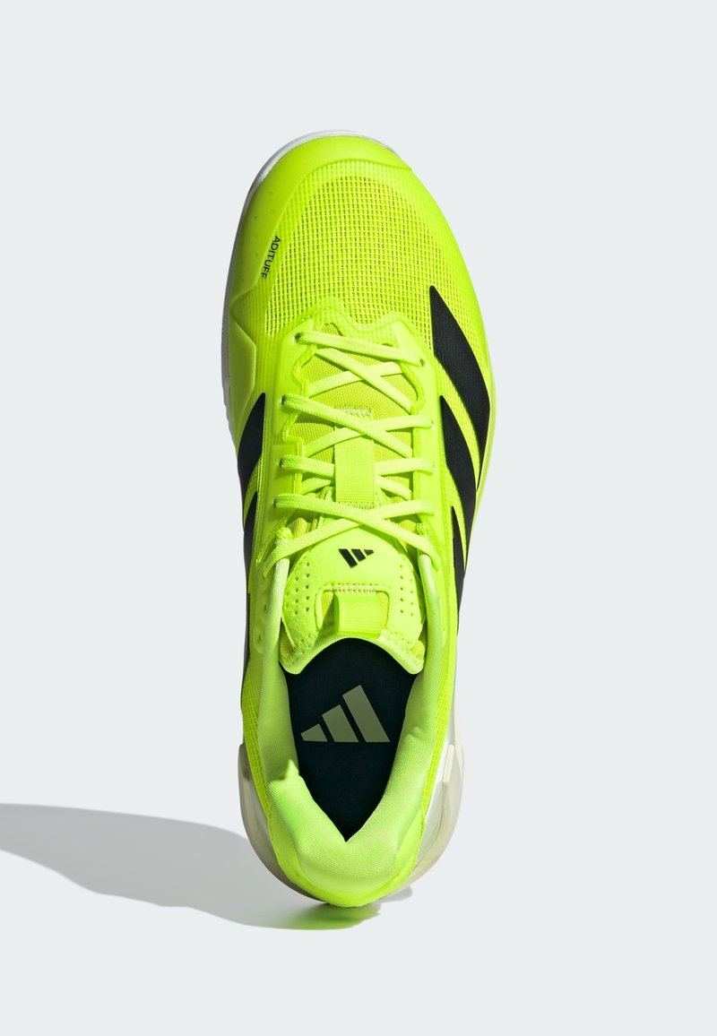 Chaussure de sport jaune néon avec des accents noirs, tige en mesh, bout rond, col rembourré et lacets texturés, arborant un logo sur la languette.