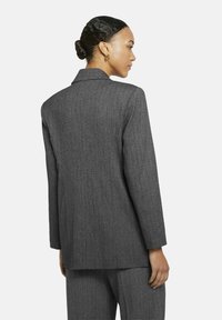 Grijze op maat gemaakte blazer van gestructureerde stof, met een notch-kraag, lange mouwen en een recht gesneden achterkant.