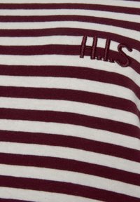 Bordo in bela pruga blaga tkanina z mehko teksturo, ki vsebuje vezeno podrobnost "H.I.S." na levi strani.