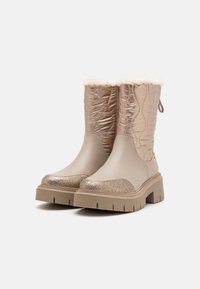 Beige ankelstøvler med kviltet metallisk tekstil, kunstig pels krage og glitrende tådetaljer. Kraftig gummisåle med rillet mønster.