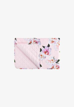 Gesteppte rosa Decke mit großen weißen und rosa Blumenmustern, gefaltet, um eine strukturierte, gestickte Rückseite zu zeigen.