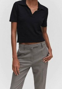 Czarna koszulka polo krótki rękaw z kołnierzykiem, połączona z spodniami w szaro-czarną kratkę houndstooth. Slim fit, dzianinowa struktura.