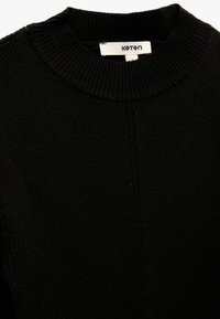 Suéter de punto negro con cuello acanalado, tejido texturizado y un detalle de costura que recorre verticalmente la parte delantera. Etiqueta de la marca visible.