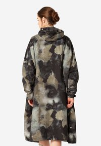 Larga gabardina con capucha en una mezcla de negro, gris y beige con un corte suelto y detalles de botones a presión. Material impermeable.