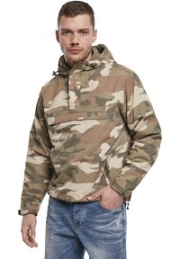 Veste camouflée en beige, vert et marron. Dotée d'un design à enfiler, d'une capuche, d'une poche frontale et d'une fermeture éclair sur le côté pour un accès facile. Texture de tissu lisse.