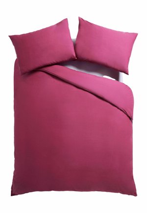 Letto matrimoniale con copripiumino rosa brillante parzialmente piegato indietro e due cuscini abbinati su sfondo bianco.
