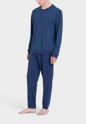 Il completo da loungewear blu navy include una maglia a maniche lunghe con un piccolo bottone e un motivo a pois bianchi, abbinata a pantaloni larghi e solidi blu navy.