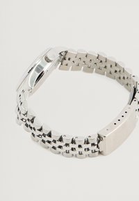 Sølv metal ur med en poleret finish, der har et rundet urkasse, justerbar ledarmbånd og en sikker låsemekanisme.