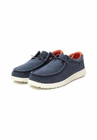Zapatos de tela azul marino con forro naranja, con forma redondeada, suela de goma blanca y simples detalles de cordones en la parte superior.