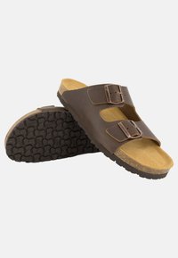Sandales en cuir marron avec deux sangles réglables, semelle en liège et semelle en caoutchouc noir texturée. Présente un design simple avec des accents minimes.