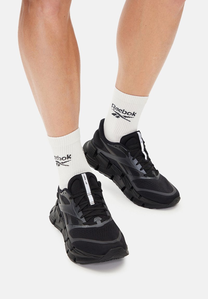 Mustad võistlusjalanõud, mis on valmistatud võrgust ja kummist tekstureeritud tallaga. Omavad sujuvat disaini ja valgeid aktsente ning on kombineeritud valgete sokkidega.