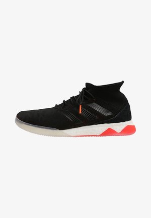 Chaussure de sport noire montante avec dessus en maille, rayures noires, semelle blanche rembourrée et accents rouges sur la semelle et les embouts des lacets.