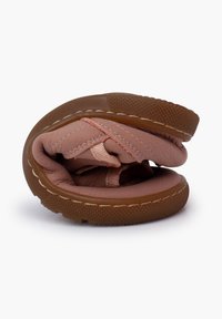 Rosa Lederschuhe mit einem weichen Innenraum, flexiblem Design und einer braunen Gummisohle. In gefaltetem Zustand sind Nähdetails und Texturen sichtbar.