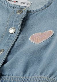 Světle modrá džínová košile se stříbrnými knoflíky a výšivkou ve tvaru pastelového srdce na levé straně. Vyrobena z 99 % bavlny.