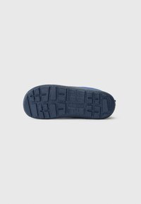 Marineblaues Schuhsohle mit gemustertem Profil und "reima"-Branding, von unten auf einem schlichten weißen Hintergrund gezeigt.