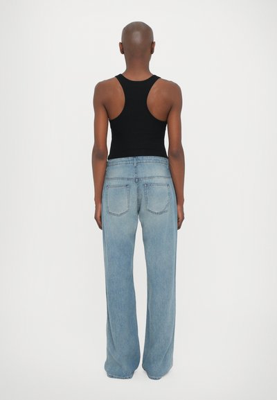 Svart linne och ljusblå vida jeans, i denim material, blekt tvätt, två bakfickor och synliga sömnadsdetaljer.
