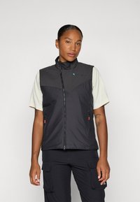 Gilet leggero nero con collo alto, frontale zip e tasche laterali. Presenta un pannello grigio a contrasto e un branding minimale.