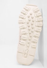 Svetle růžová teniska s texturovanou podrážkou s výraznými výstupky a logem, prodyšným svrškem s perforacemi a hladkými detaily.