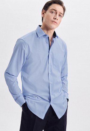 Hellblaue Langarmbluse mit Kragen, einer einzelnen Brusttasche, Knopfverschluss und kontrastierendem schwarzen Innenkragen. Glatte Stofftextur.