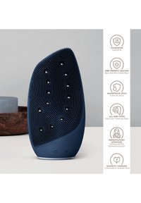 Silicone rengöringsapparat i marinblått, ergonomisk form, texturerad yta med upphöjda punkter, med laddningsport och knappar.