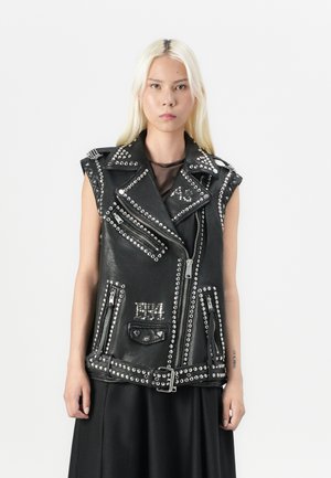 Black leather sleeveless vest with silver studs, multiple zippers, and pockets. Features a belted waist and asymmetrical collar design.