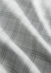 Tejido de cuadros gris claro que presenta un tejido texturizado, con líneas sutiles y un acabado suave, diseñado para aplicaciones versátiles.