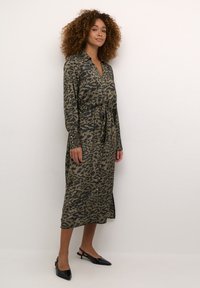 Abito camicia in stampa leopardata verde e nera, maniche lunghe, vita cintrata, lunghezza a metà polpaccio e spacco laterale all'orlo.