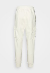 White jogger pants made of soft fabric with elastic waistband, side cargo pockets, and ribbed cuffs. Minimalist design with no patterns.