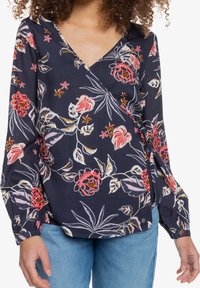 Blusa avvolgente floreale navy con stampa di fiori tropicali rosa e bianchi, maniche lunghe con polsini elastici e scollatura a V.