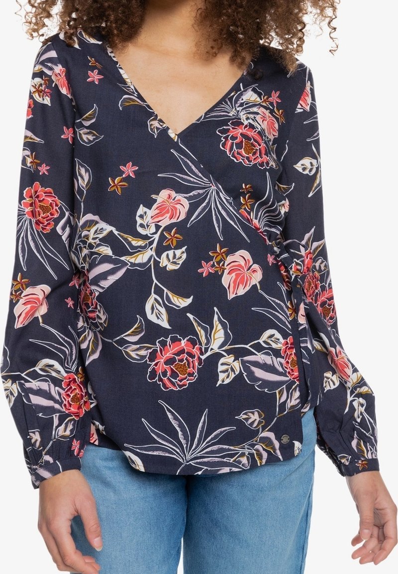 Blusa avvolgente floreale navy con stampa di fiori tropicali rosa e bianchi, maniche lunghe con polsini elastici e scollatura a V.