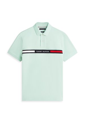 Šviesiai žalias trumpomis rankovėmis polo marškinėlis su apykakle, dviem mygtukais ir horizontalia juoda, balta bei raudona juosta per krūtinę su užrašu „Tommy Hilfiger“.