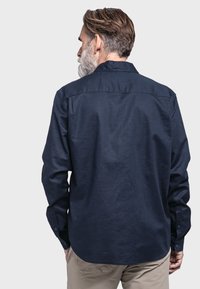 Marineblaue Langarmbluse mit schmaler Passform, geknöpften Manschetten, Rückenpasse und abgerundetem Saum, aus einem glatten Stoff mit leichtem Glanz.