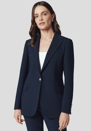 Granatowa marynarka o dopasowanym kroju, z klapami w stylu notch, dwoma przednimi kieszeniami, zapięciem na złoty guzik i subtelną fakturą materiału.