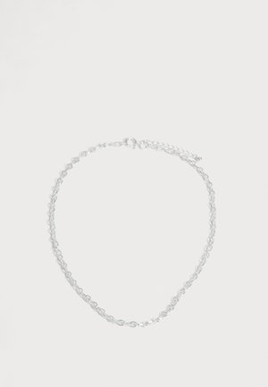 Fin collier chaîne en argent avec des maillons ovales et un petit fermoir ajustable, présenté sur un fond blanc uni.
