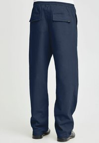 Navy blue pants with a relaxed fit, elastic waistband, and two back patch pockets. Smooth texture with straight legs and a simple design.